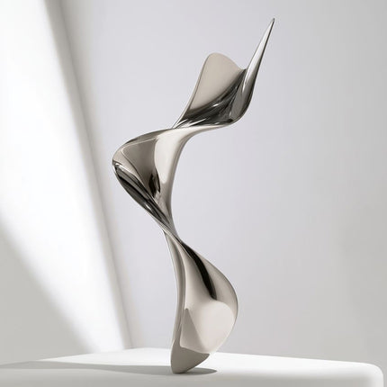 Mirror polished stainless steel twisting ribbon sculpture with an upward-reaching form on a light studio background
