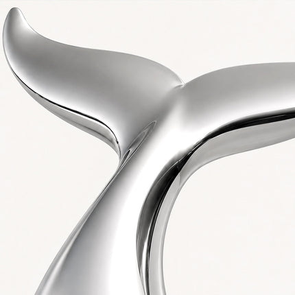 Close-up of the curved flukes and reflective surface of a mirror polished stainless steel whale tail sculpture