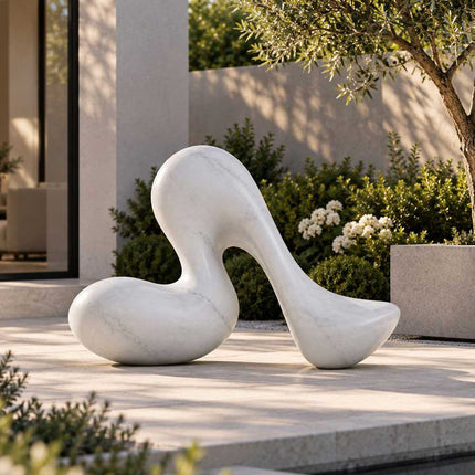 Modern abstract marble sculpture displayed in a landscaped residential garden