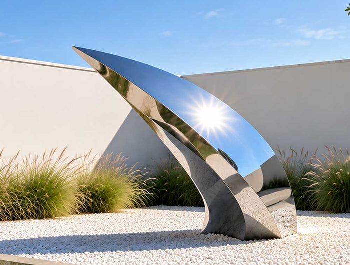 Modern stainless steel sculpture in a contemporary architectural landscape