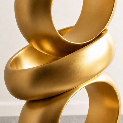 Close-up of the rounded gold bands and overlapping circular forms of an abstract ring sculpture