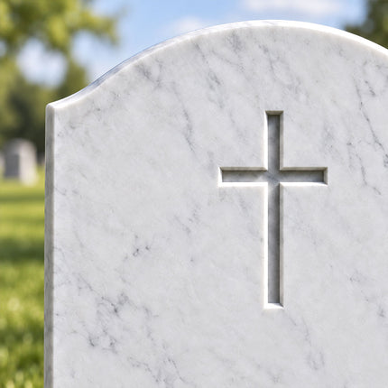 Close-up of the recessed Christian cross and gently curved top on a white marble headstone