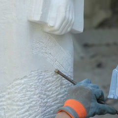Refining the surface texture and carved details of a handcrafted white marble sculpture before the polishing stage.