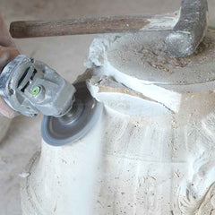 Rough shaping a marble sculpture with power tools to establish the overall form before hand carving.