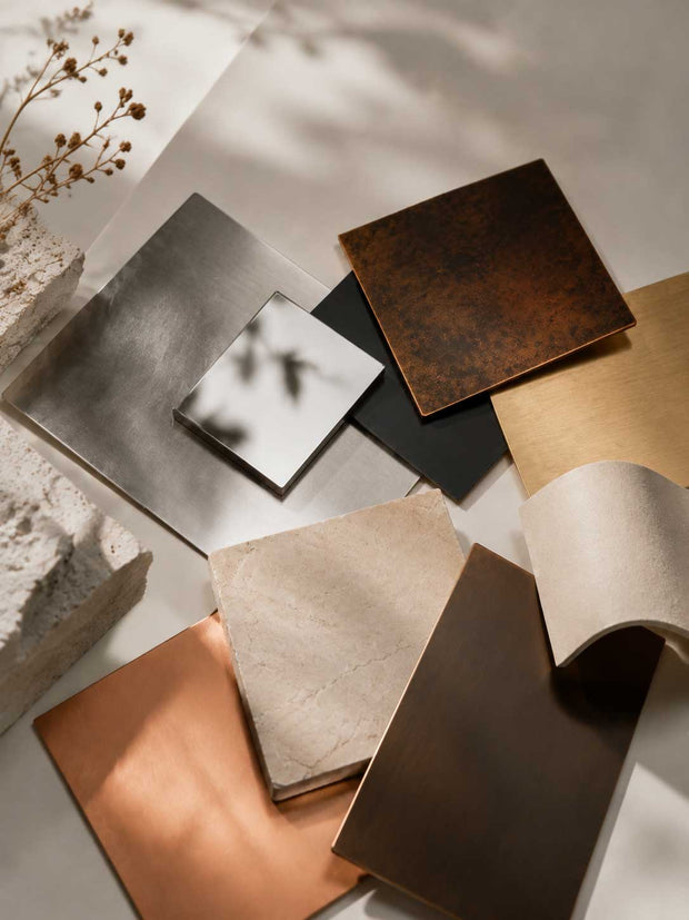 Selection of sculpture materials including stone, bronze, and stainless steel samples showing different textures and surface qualities
