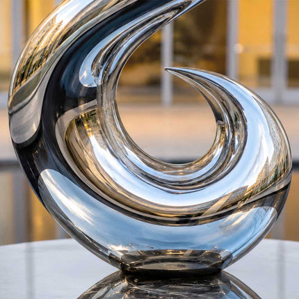 Detailed view of the reflective curved surface of a handcrafted stainless steel sculpture