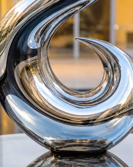 Detailed view of the reflective curved surface of a handcrafted stainless steel sculpture