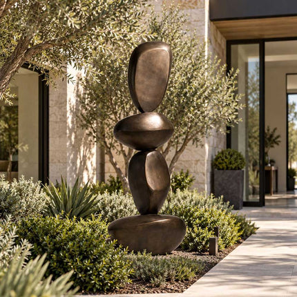Stacked bronze sculpture with rounded organic forms in a landscaped garden