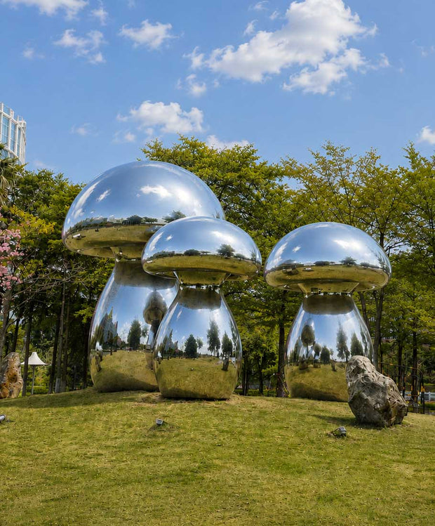 Large stainless steel mushroom sculptures installed in an urban park landscape