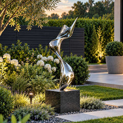 Mirror polished stainless steel ribbon sculpture on a dark stone pedestal in a landscaped private garden