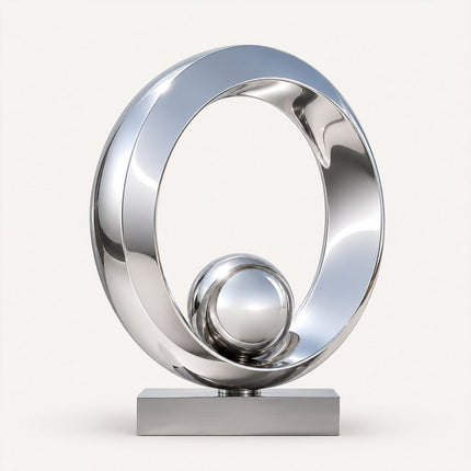 Mirror polished stainless steel ring sculpture with a reflective sphere and rectangular base.