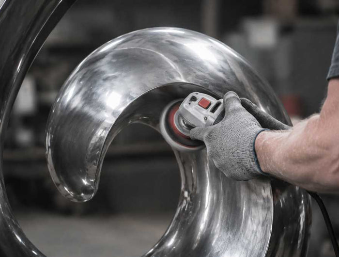 Artisan polishing a stainless steel sculpture during the handcrafted production process