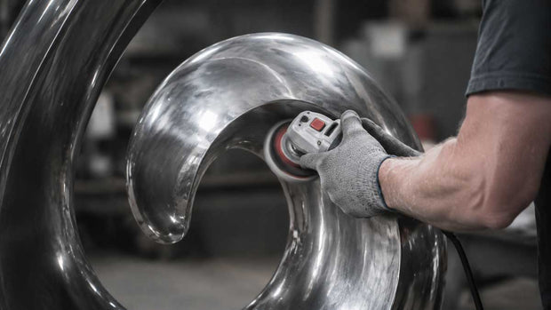 Artisan polishing a stainless steel sculpture during the handcrafted production process