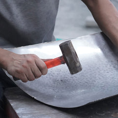 Artisan forging stainless steel sculpture into organic artistic form