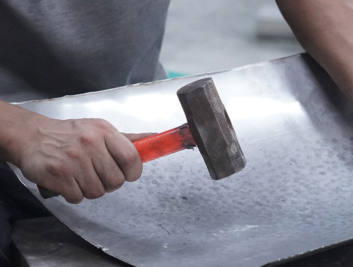 Artisan forging stainless steel sculpture into organic artistic form