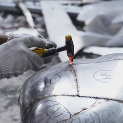 Artisan welding stainless steel sculpture components during structural assembly