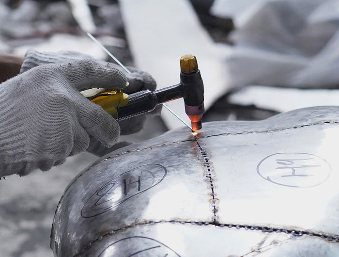 Artisan welding stainless steel sculpture components during structural assembly