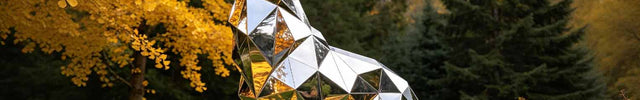 Stainless steel sculpture in modern architectural landscape reflecting sky and surrounding environment.