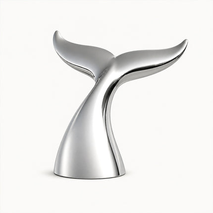 Mirror polished stainless steel whale tail sculpture with broad upturned flukes on a white background