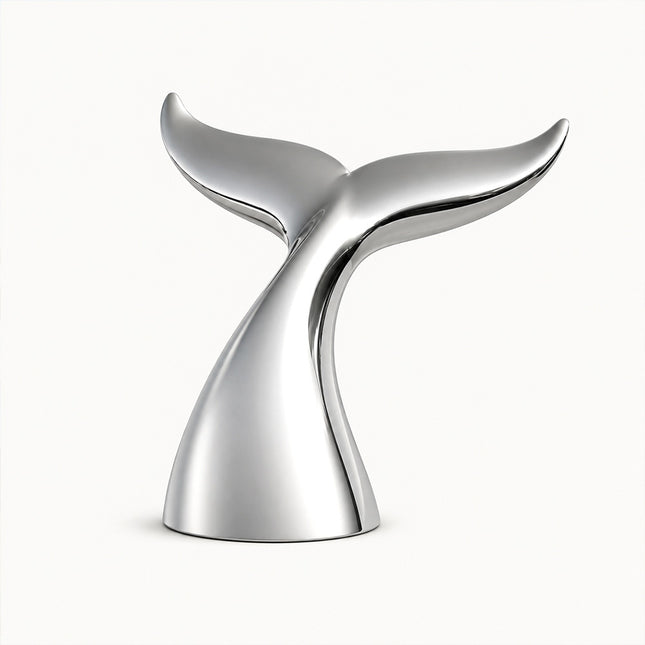 Mirror polished stainless steel whale tail sculpture with broad upturned flukes on a white background