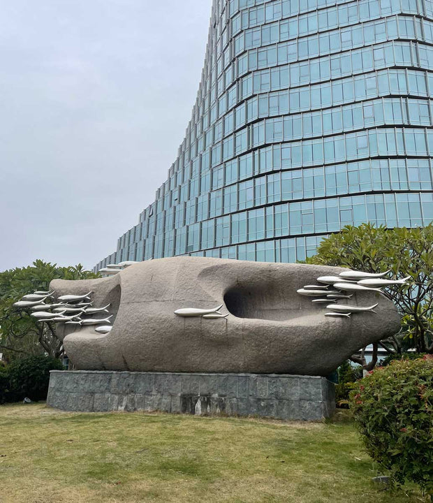 Stone sculpture with stainless steel fish viewed from an angled perspective